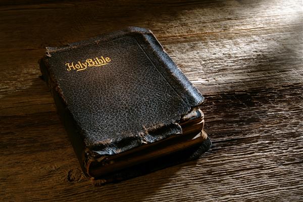 کتاب مقدس عتیقه و آسیب دیده مقدس در نیمکت چوب فرسوده در یک کلیسای قدیمی