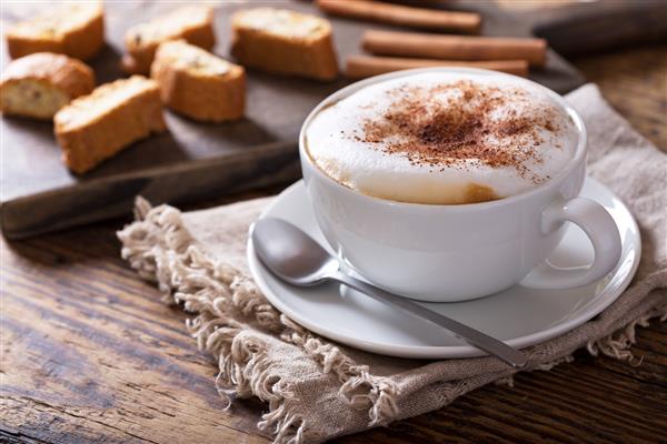 فنجان قهوه کاپوچینو روی میز چوبی