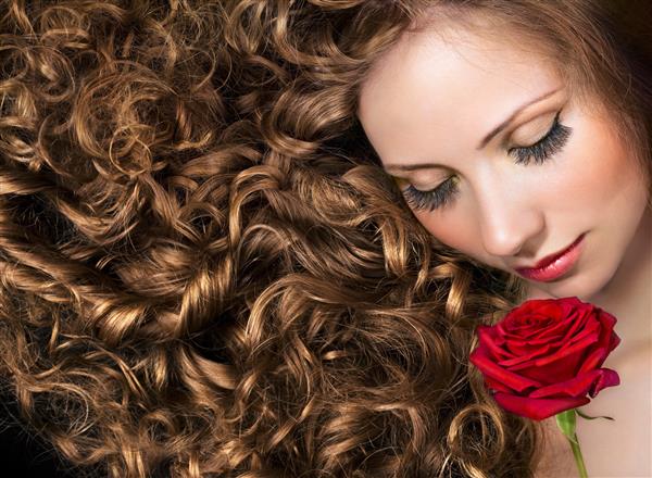 مدل زیبایی با موهای فرفری بلند و گل رز قرمز
