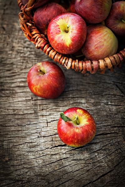 برداشت تازه سیب تم طبیعت با انگور قرمز و سبد در زمینه چوبی مفهوم میوه طبیعت