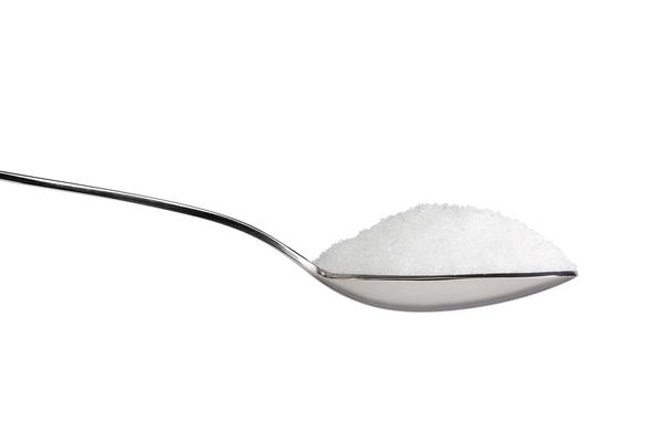 نمک یا شکر روی یک قاشق چای خوری جدا شده روی زمینه سفید