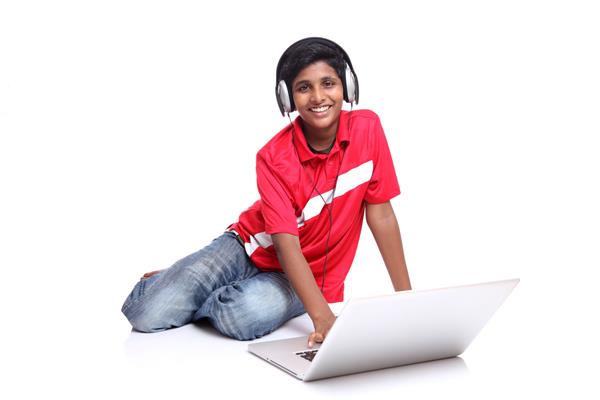 پسر نوجوان با لپ تاپ روی زمینه سفید نشسته است