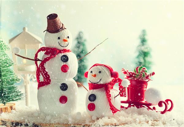 یک پس زمینه جشن زمستانی با دو آدم برفی خوشحال ساخته شده از گلوله های نخ دکمه ها و توری کارت کریسمس فضای کپی