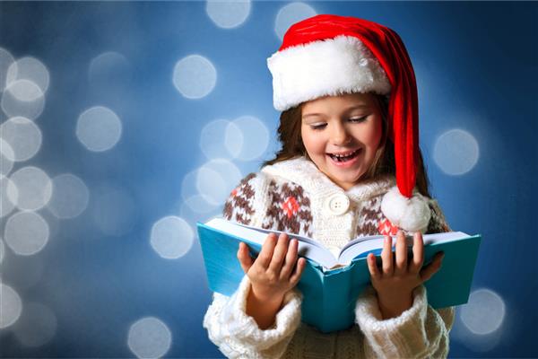 کودک سورپرایز که کتاب جادویی کریسمس را باز می کند مفهوم تعطیلات کریسمس