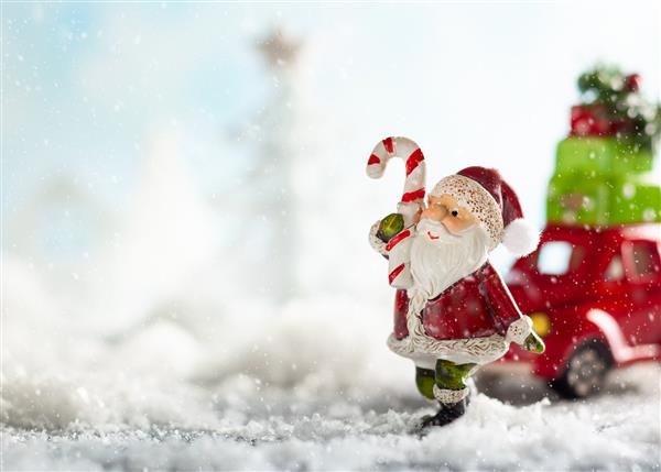 بابانوئل و ماشین اسباب بازی قرمز که هدیه های کریسمس را در چشم انداز برفی حمل می کنند مفهوم کریسمس با فضای کپی