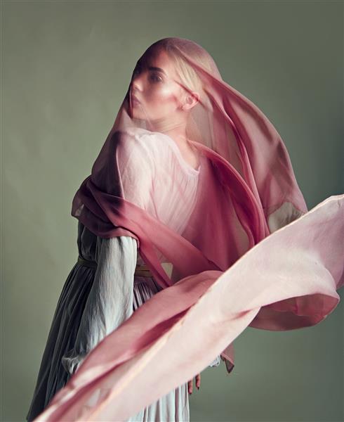 یک دختر جوان و زیبا با لباس نوعی پارچه ابریشمی با پارچه ای از پارچه نازک که در باد ایجاد می شود پوشیده شده است مد زیبایی آرایش لوازم آرایشی سالن زیبایی سبک مراقبت شخصی
