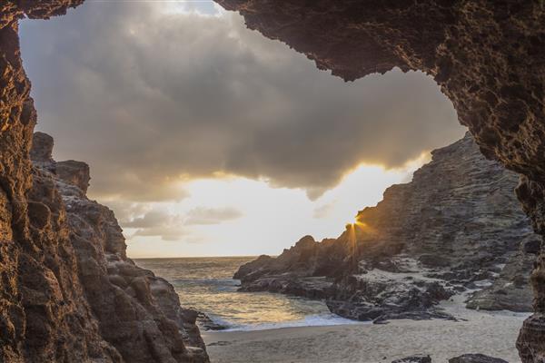 نمای طلوع خورشید از غار هالونا ساحل ابدیت از داخل یک لوله گدازه