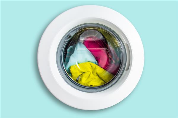 نمای ماشین لباسشویی از جلو جدا شده است درب از ماشین لباسشویی با طبل همراه با لباس مفهوم شستشو و مراقبت از تمیزی لباس ها