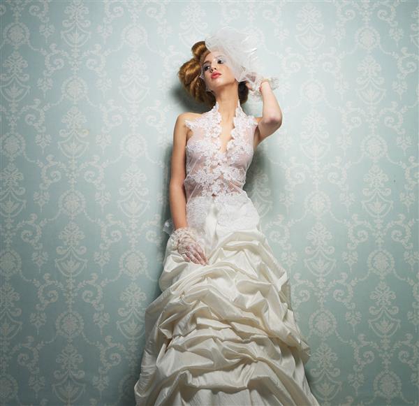 عروس زیبا با لباس عروس سفید ظریف و دستی به سر