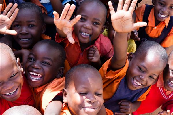 اوگاندا گروهی از کودکان دبستانی خوشحال که لبخند می زنند می خندند و تکان می خورند آنها لباس فرم مدرسه دارند