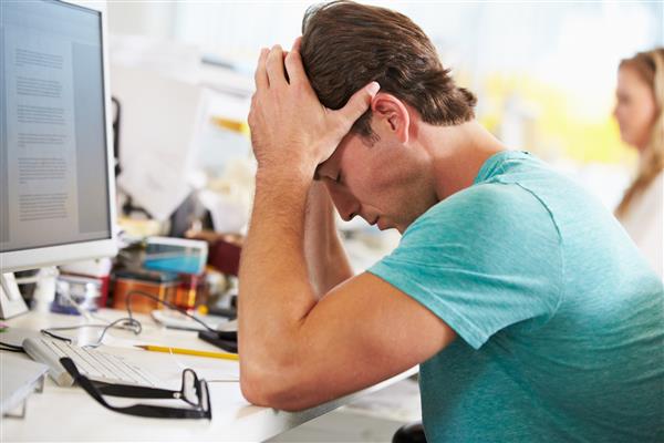 مردی استرس که در دفتر کار در دفتر خلاق مشغول کار است