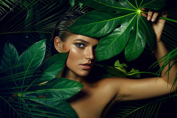 یک دختر برنزه زیبا با آرایش طبیعی و موهای خیس در جنگل در میان گیاهان عجیب و غریب ایستاده است مد زیبایی سلامتی محیط زیست آرایش مراقبت شخصی مو طبیعت