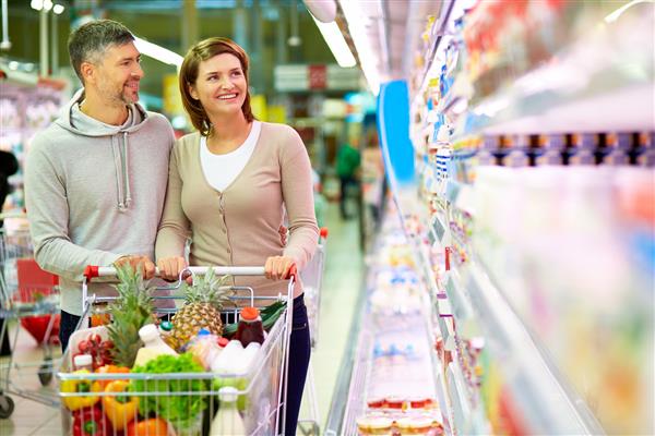 تصویری از زن و شوهر خوشحال با سبد خرید در سوپرمارکت