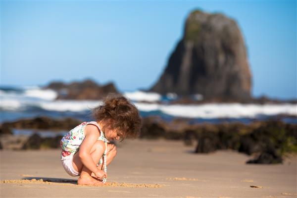 یک کودک خردسال در ساحل نیو ساوت ولز استرالیا در شن بازی می کند