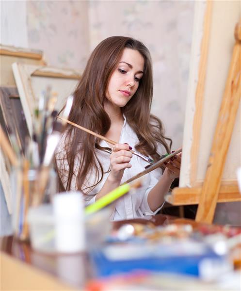 هنرمند زن مو بلند هر چیزی را روی بوم در استودیو نقاشی می کند