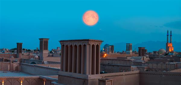 شهر تاریخی یزد با برج های معروف باد در پس زمینه ماه کامل در ساعت آبی گرگ و میش- YAZD IRAN عناصر این تصویر تهیه شده توسط ناسا