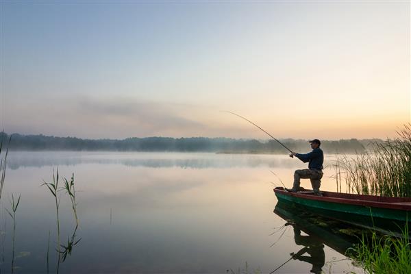 ماهیگیر در حال صید ماهی در سحر مه آلود