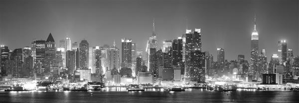 شهر نیویورک در مرکز شهر منهتن در شب آسمان سیاه و سفید را نشان می دهد و آسمان خراش هایی با انعکاس بر روی رودخانه هادسون روشن است