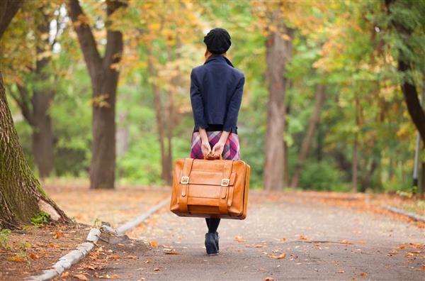 دختر با چمدان در فضای باز پاییز