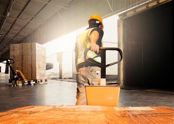 جعبه های حمل و نقل کارگر انبار در حال تخلیه کالاهای حمل پالت به یک کانتینر کامیون صنعت حمل و نقل کالا تدارکات و حمل و نقل است