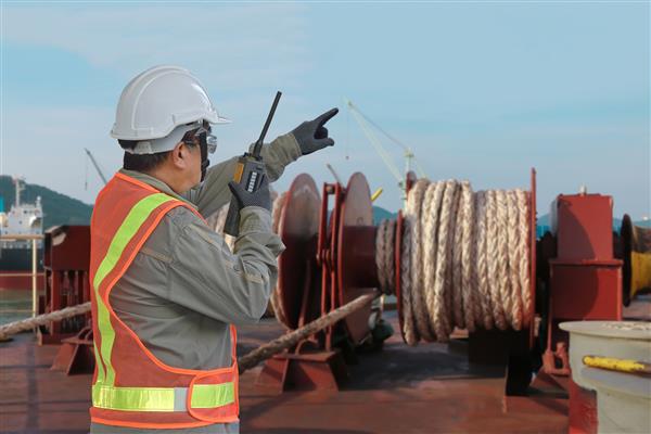 کارگر خدمه در کشتی تانکر در دست نگه داشتن واکی مخابرات طناب پهلوگیری در بسته نرم افزاری در وینچ نگهداری فشار کشتی جذب ایمنی به تجهیزات ایمنی در امتداد کشتی به اسکله بندر