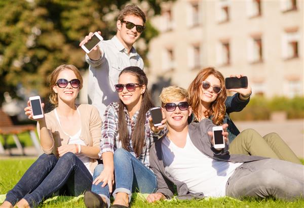 آموزش فناوری اینترنت تعطیلات تابستانی شبکه های اجتماعی و مفهوم نوجوانان - گروهی از نوجوانان دارای تلفن های هوشمند