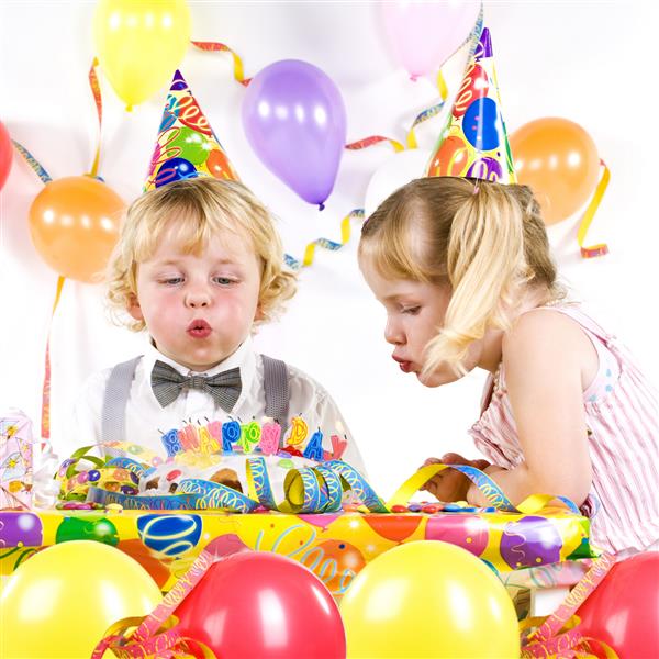 دو کودک در حال مهمانی در حال دمیدن شمع های کیک