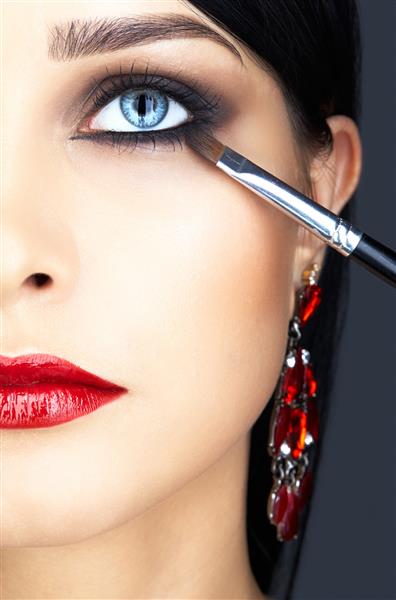 عکس کلوزآپ از صورت و آرایش زنانه که از آرایش ریمل برای مژه های چشم استفاده می کند