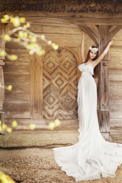 مدل مد لباس سفید بلند سبک محلی مردمی عروس زنانه عروس هیتن پرتره زیبایی بیش از دیوار خانه چوبی قدیمی