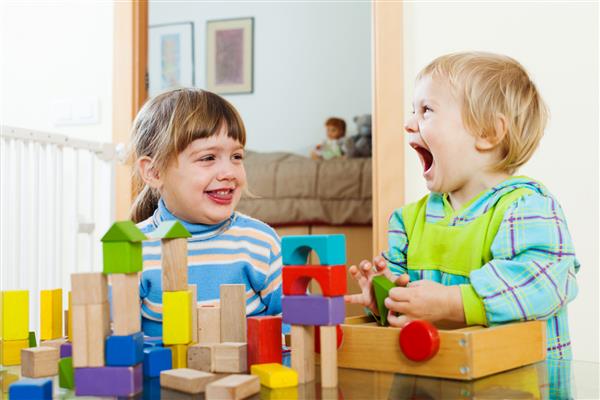 خواهران و برادران خوشحال احساسی که در فضای داخلی خانه با اسباب بازی های چوبی بازی می کنند