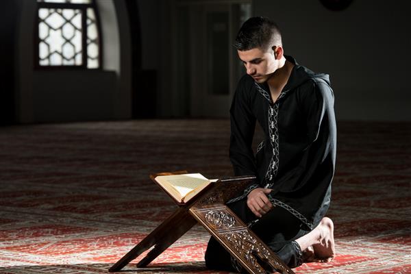 یک جوان مسلمان در حال خواندن قرآن