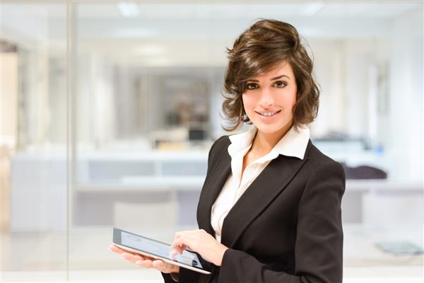 پرتره زن جوان زیبا و تجاری با رایانه لوحی در دفتر