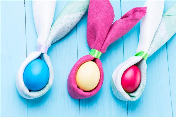 تخم های عید پاک و شکل گوش های خرگوش روی زمینه ای چوبی آبی تمرکز انتخابی تصویر رنگی