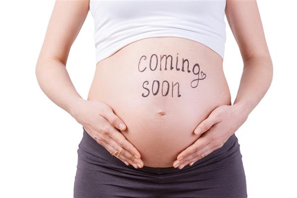 به زودی تصویر بریده شده از زن باردار که به زودی بر روی شکم ایستاده است و روی سفید قرار گرفته است