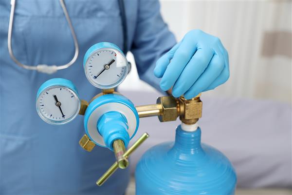 کارگر پزشکی در حال بررسی مخزن اکسیژن در اتاق بیمارستان کلوزآپ