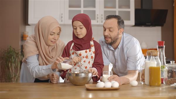 زن و شوهر مسلمان با دختر کوچکشان در آشپزخانه آشپزی می کنند مفهوم آشپزی به عنوان یک خانواده تفریح ​​با هم