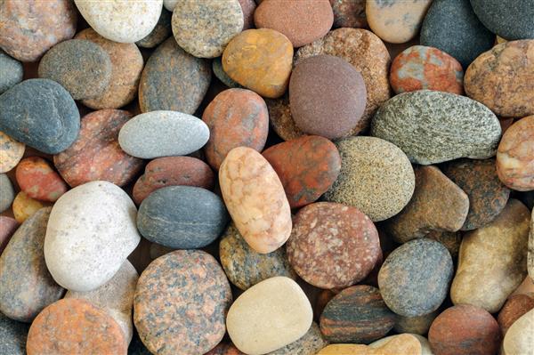 سنگهای کوچک دریا با رنگهای مختلف نمای از بالا پس زمینه چکیده