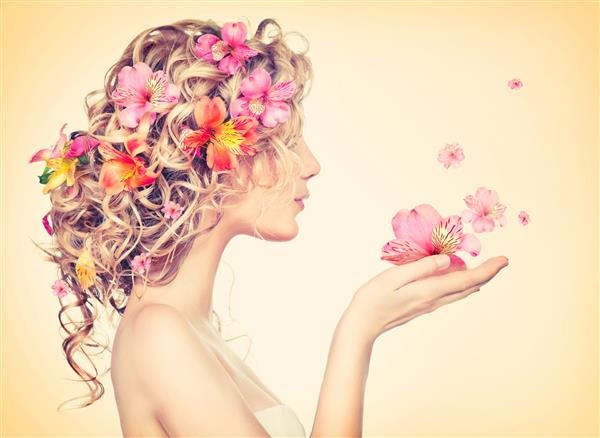 مدل زن گلهای زیبایی را در دستان خود می گیرد مدل مو با گل پرتره دخترانه فانتزی در رنگ های پاستلی