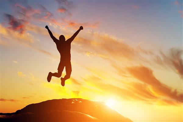 مرد خوشبختی که از شادی در قله کوه پرتگاه هنگام غروب آفتاب می پرید موفقیت برنده خوشبختی