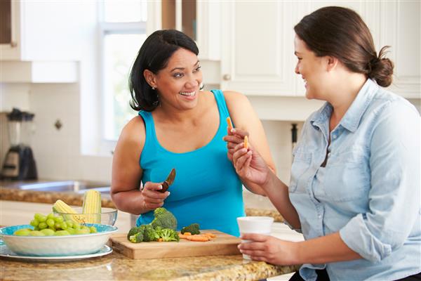 دو زن دارای اضافه وزن در رژیم غذایی آماده سازی سبزیجات در آشپزخانه