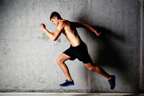 عکس یک ورزشکار عضلانی در حال دویدن روی زمینه بتونی