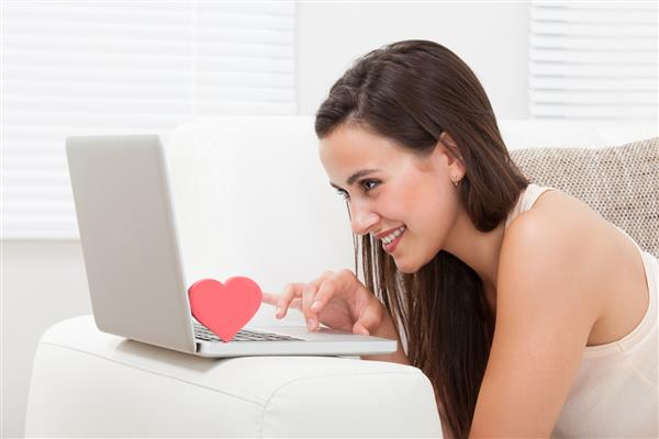 نمای جانبی دوستیابی زن جوان و زیبای آنلاین با لپ تاپ در خانه