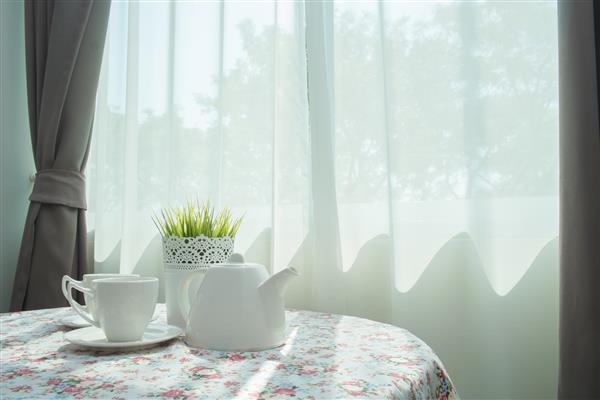 چای در نزدیکی پنجره با اشعه خورشید تنظیم شده است