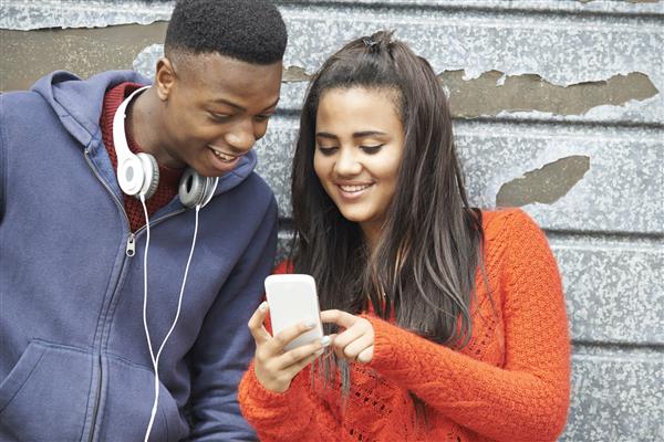 زن و شوهر نوجوان پیام متنی را در تلفن همراه به اشتراک می گذارند