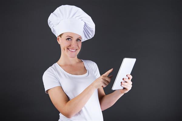 آشپزی فناوری و مفهوم غذا - آشپز زن نانوای خندان با رایانه لوحی رایانه