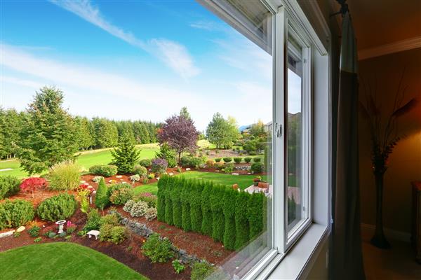 طراحی چشمگیر حیاط خلوت با درختان بوته ها و خاک اره نمایی زیبا از پنجره اتاق خواب