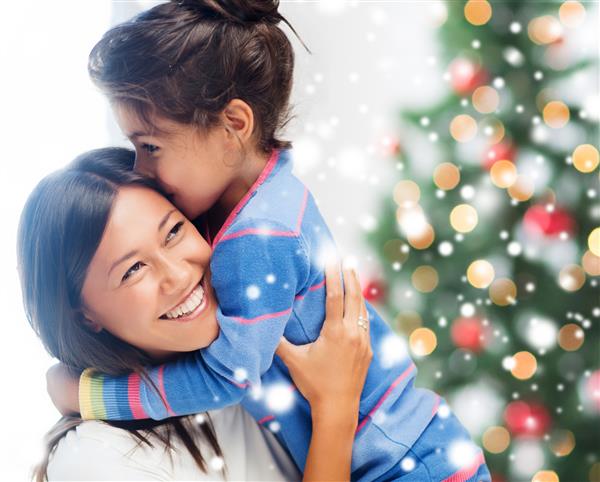 مفهوم کودکی شادی کریسمس خانواده و مردم - دختر و مادر خندان در فضای داخلی در آغوش گرفته اند