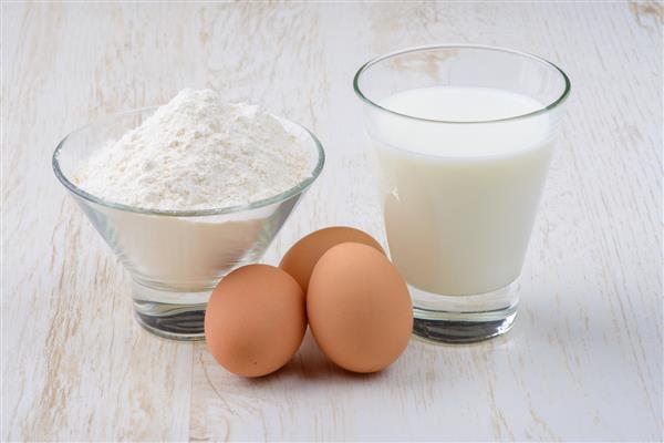 مواد لازم برای پخت تخم مرغ آرد و شیر روی میز