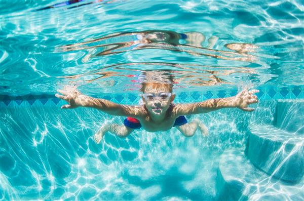 تفریح ​​پسر جوان زیر آب در استخر شنا با عینک محافظ سرگرمی تعطیلات تابستانی