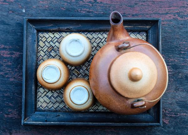 قابلمه چای و فنجان ها روی میز چوبی